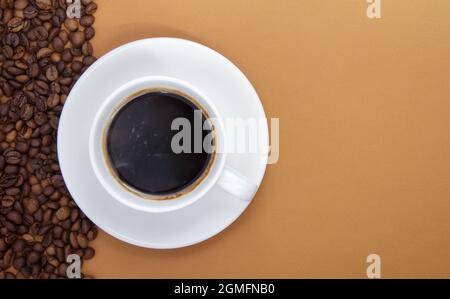 White cup of Americano black coffee without milk with a bunch of roasted coffee beans scattered from paper packaging. Coffee background, top view with Stock Photo