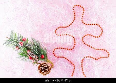 Symbol Christmas and Happy New Year figure christmas tree with red beads on tinsel. Christmas beads on pink tinsel. Holiday concept. Top view Stock Photo