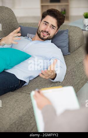 emotional man lies on couch talking to therapist Stock Photo