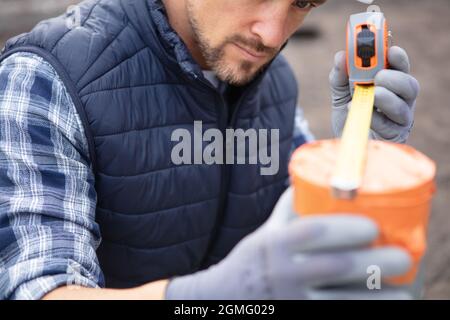 young tradesman using tape measure to measure waste pipe Stock Photo