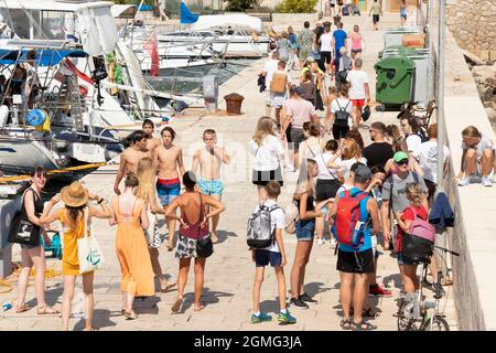 Prvic Luka, Croatia - August 25, 2021: Young people waiting, standing and walking on the pier, from above Stock Photo