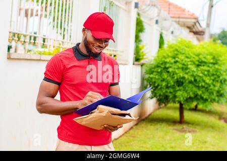 african delivery worker writing something in a manifest Stock Photo