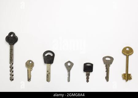 Seven types of differently shaped door keys lie in a row on a white background under clipping Stock Photo