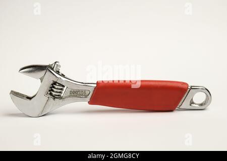 Large adjustable wrench close-up with red handle on white background Stock Photo