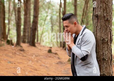 Thoughtful man clasping his hands together near his mouth.  Stock Photo