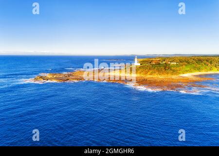 White lighthouse on a hill of Norah Head of Australia NSW Central coast - aerial view over bays and pacific ocean. Stock Photo