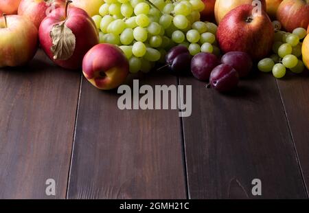 Ripe fresh apples, nectarines, plums and grapes on dark wooden surface Stock Photo