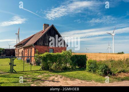 A symbiosis of tradition and modernity. Wind farm and small farm. Windmills producing electricity growing from the fields Stock Photo