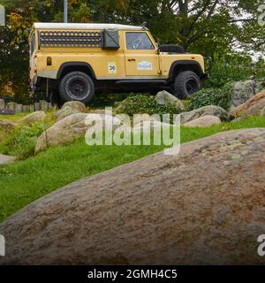 Range Rover Defender, classic English off-road vehicle on round granite rocks, with spare canister and mud boards on the side in Schöningen, Germany, Stock Photo