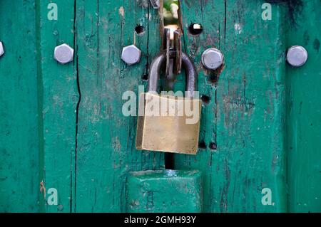 Metal padlock on wooden door. Close up details of metal padlock on wooden door. Old vintage lock on a wooden door. Stock Photo