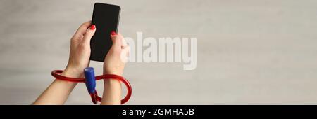 Woman with tied hands holding mobile phone closeup Stock Photo