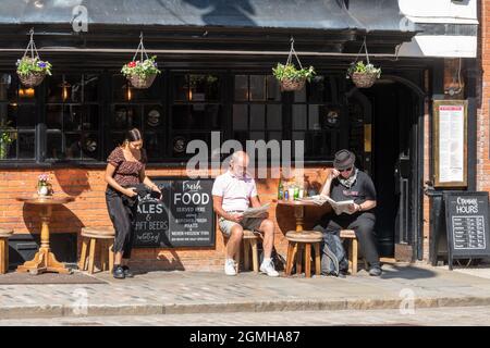 The Three Pigeons pub on the Guildford High Street, Surrey, UK, with people sitting enjoying drinks outside on a sunny day Stock Photo