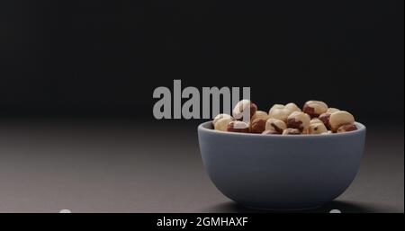 roasted hazelnuts in blue bowl on black background, wide photo Stock Photo