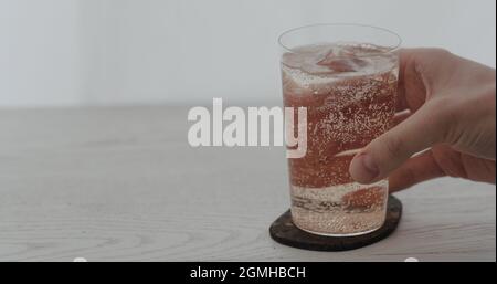 man take rose water over big ice rock in tumbler glass, wide photo Stock Photo