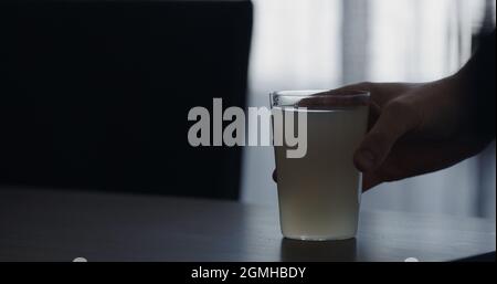 closeup man hand take lemonade in a tumbler glass from walnut table with copy space, wide photo Stock Photo