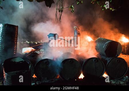 Worker mixing pitch in boiler for melting tar, set up for pitch jointing with molten bitumen. Stock Photo