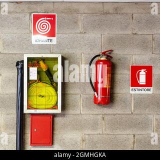hydrant and fire extinguisher with relative signs hanging on the wall Stock Photo