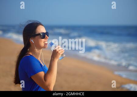 woman drinks water on the sea beach Stock Photo