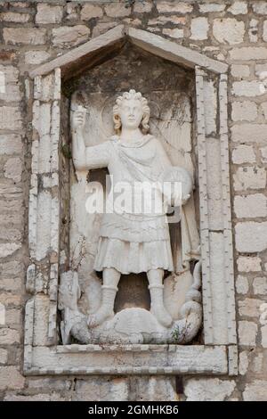 Sibenik, Croatia - August 25, 2021: Stone sculpture of Saint Michael the Archangel killing a dragon, detail on stone and glass public library building Stock Photo