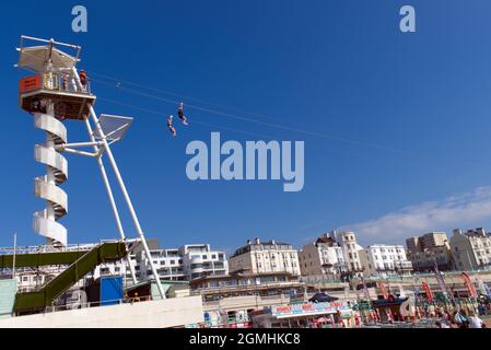 Two people riding the Zip Wire on Brighton beach on a sunny and warm day at this popular seaside resort. Stock Photo