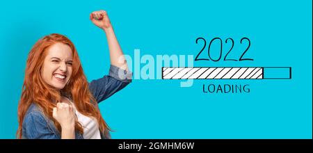 Young red haired woman gesturing YES, waiting for New 2022 Year to start on blue background, collage with loading bar Stock Photo