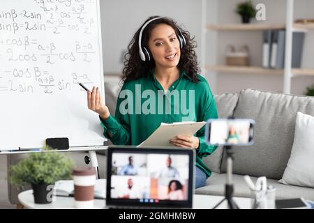 Young teacher showing board, giving virtual lecture to students Stock Photo