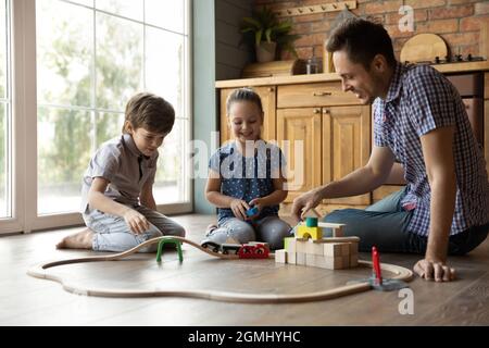 Joyful adorable little kids playing toys with father.