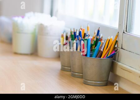 Colored pencils and markers in a metal box on a wooden table Stock Photo