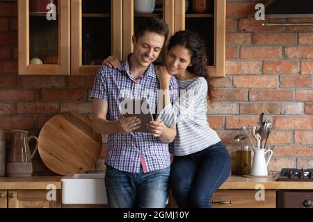 Affectionate happy young family couple using digital touchpad gadget. Stock Photo