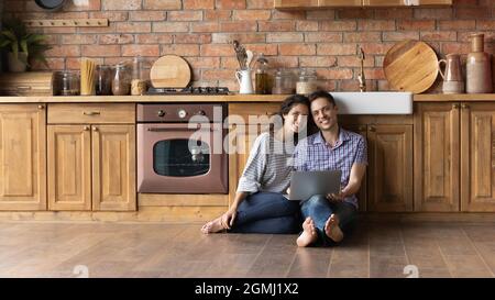 Portrait of smiling young hispanic family couple sitting on floor. Stock Photo