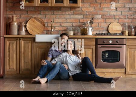 Relaxed happy millennial family couple sitting on floor. Stock Photo