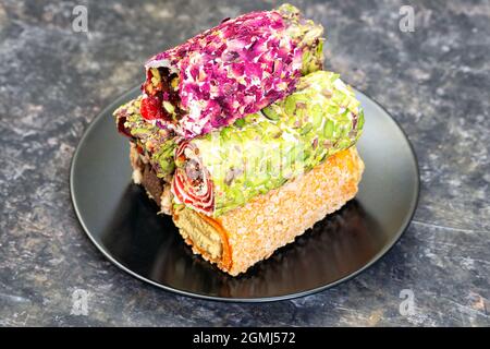 Black plate with assorted turkish delight on a dark table. Premium turkish dessert. Stock Photo