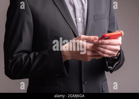 businessman holding a phone with red case. High quality photo on a gray background Stock Photo