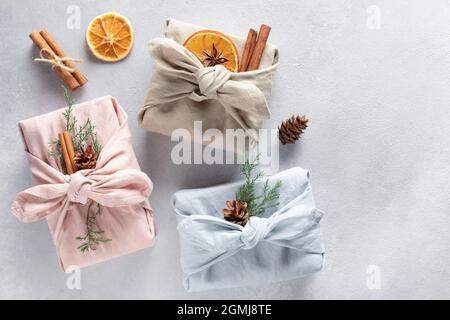 Three furoshiki style wrapped gifts with natural decor. Zero waste. Stock Photo