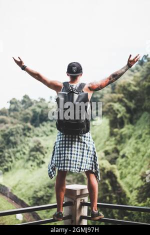 Guy with a tattoo all over his arm stands on the railing at the observation deck in the jungle. Scenic view in Georgia. High quality photo Stock Photo
