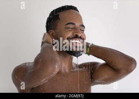 Happy African man standing under running water enjoy morning shower Stock Photo