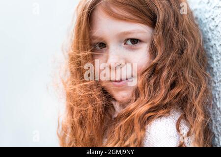 Portrait of a cute, little, freckled, ginger girl in white dress Stock Photo