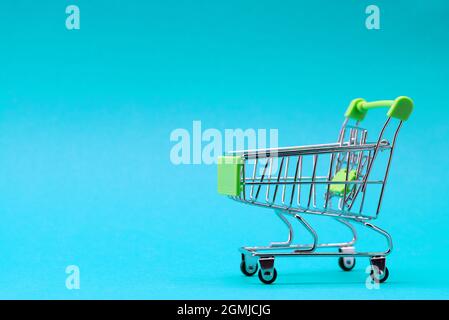 Shopping trolley on a blue background. Green color. Place for an inscription. Shopping concept Stock Photo
