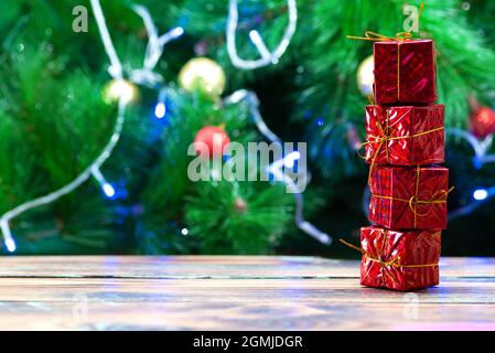 Traditional christmas pine tree with holiday decorations in the background and a stack of small red gifts in the foreground Stock Photo