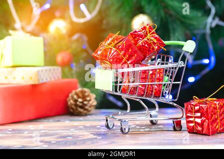 Mini shopping basket with red christmas gifts on the background of the christmas tree Stock Photo