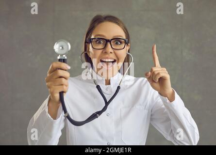 Portrait of happy doctor with stethoscope pointing one finger up struck by a great idea Stock Photo