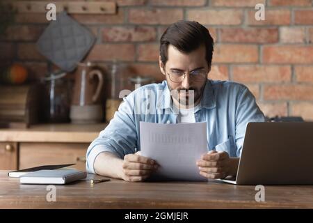 Confident man in glasses reading document, analyzing financial report Stock Photo