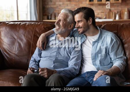 Happy dreamy two generations of men looking in distance Stock Photo