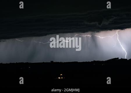 Horizontal and vertical lightning bolts pierce the sky above the mountains of the Alps in Austria Stock Photo