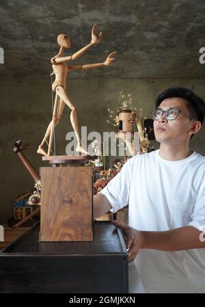 (210919) -- SHIJIAZHUANG, Sept. 19, 2021 (Xinhua) -- Li Zhanlong shows a wooden mechanical installation at his studio in Luquan District of Shijiazhuang, north China's Hebei Province, Sept. 14, 2021. Li Zhanlong is a wooden mechanical installation designer in Shijiazhuang. After graduation, Li once worked as a salesman and ran an online shop. In 2018, Li Zhanlong left his job and went to Tianjin to learn carpentry skills. The wooden mechanical installation consists of a wooden figure and a mechanism device that can make the installation move. By shaking the handle or pressing the button, t Stock Photo