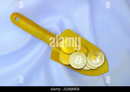 Gold bitcoin coins on a golden shovel on white background Stock Photo