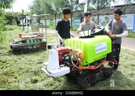 (210919) -- BEIJING, Sept. 19, 2021 (Xinhua) -- Zhou Zhan (C), Zheng Yi (L) and Lin Guihai, college students from China Agricultural University, check an autopilot sprayer in Future Orchard in Xiying Village of Yukou Township in Pinggu District of Beijing, capital of China, Aug. 25, 2021. 'Future Orchard' is a high-tech orchard founded by local government with China Agricultural University and other enterprises. The orchard has a lab and four hectares of land with peach and kiwi trees. With the help of intelligent monitoring system for data analysis, accurate management and visual diagnosis on Stock Photo