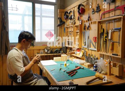 (210919) -- SHIJIAZHUANG, Sept. 19, 2021 (Xinhua) -- Li Zhanlong makes wooden mechanical installation at his studio in Luquan District of Shijiazhuang, north China's Hebei Province, Sept. 14, 2021. Li Zhanlong is a wooden mechanical installation designer in Shijiazhuang. After graduation, Li once worked as a salesman and ran an online shop. In 2018, Li Zhanlong left his job and went to Tianjin to learn carpentry skills. The wooden mechanical installation consists of a wooden figure and a mechanism device that can make the installation move. By shaking the handle or pressing the button, the Stock Photo