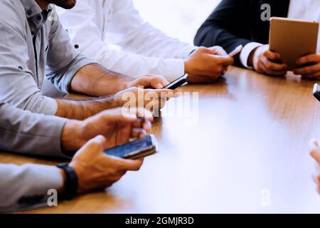 Close-up of business men and woman all using their phone on desk inside office space Stock Photo