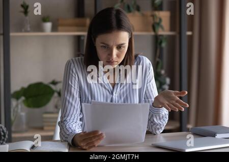 Unhappy dissatisfied young woman reading bad news in letter Stock Photo